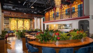 Full interior view of Cali Chilli Kitchen & Bar featuring open kitchen view, mezzanine balcony, crystal chandelier, and curved seating by Urban Box Studio