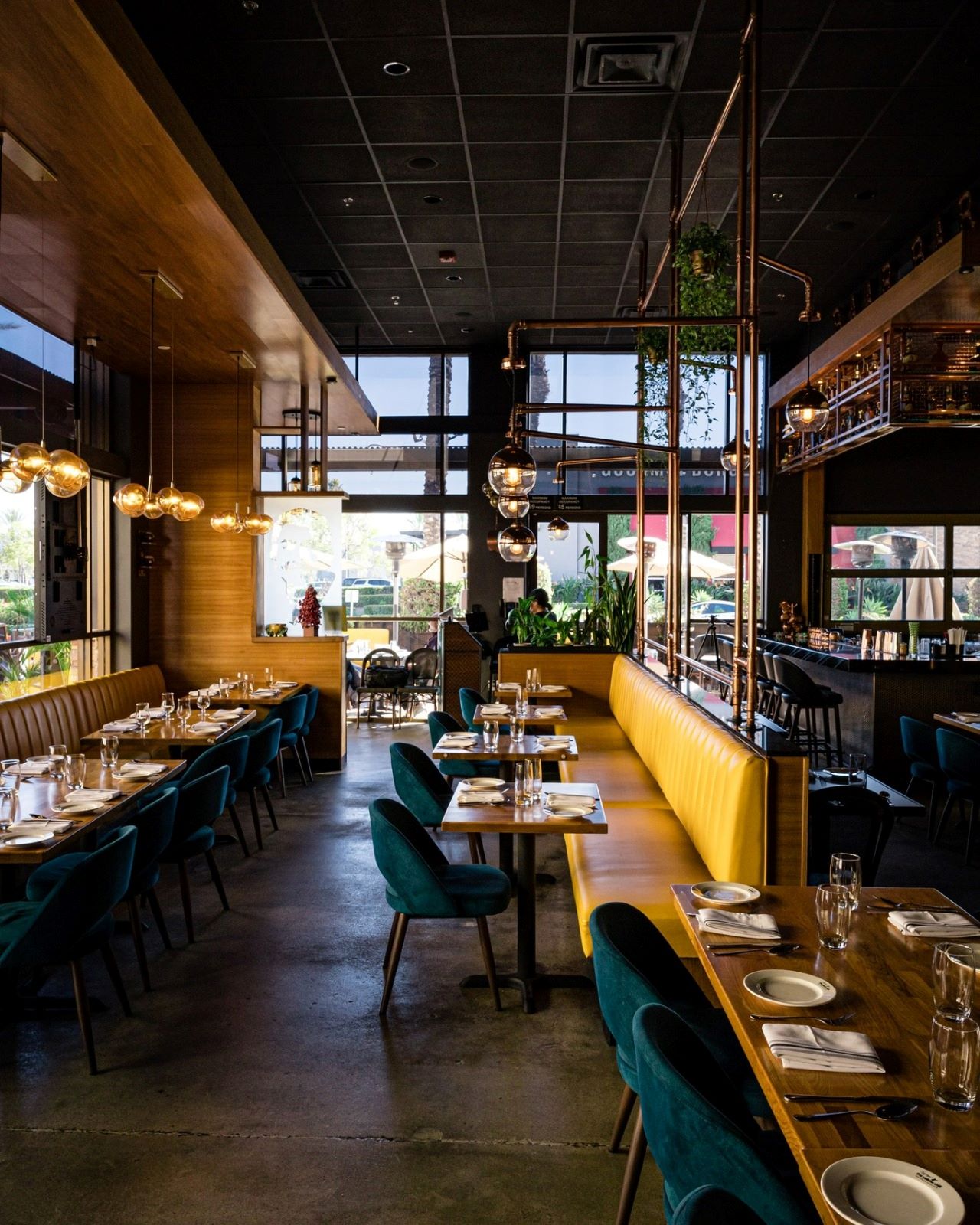 The Yellow Chilli USA interior dining area featuring yellow leather booth seating, teal velvet chairs, and copper pipe pendant lighting by Urban Box Studio