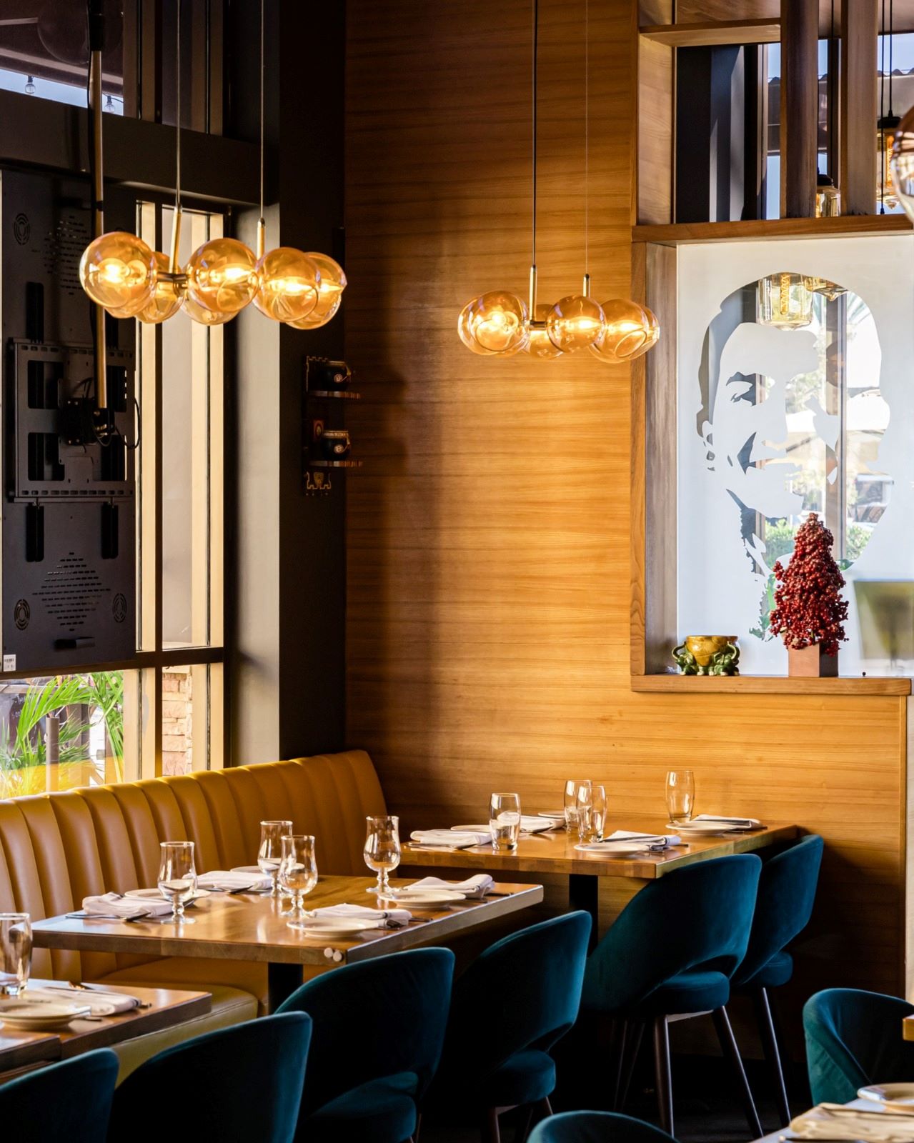 Cozy dining alcove at The Yellow Chilli USA with amber globe chandeliers, yellow leather banquette, and warm wood wall feature by Urban Box Studio