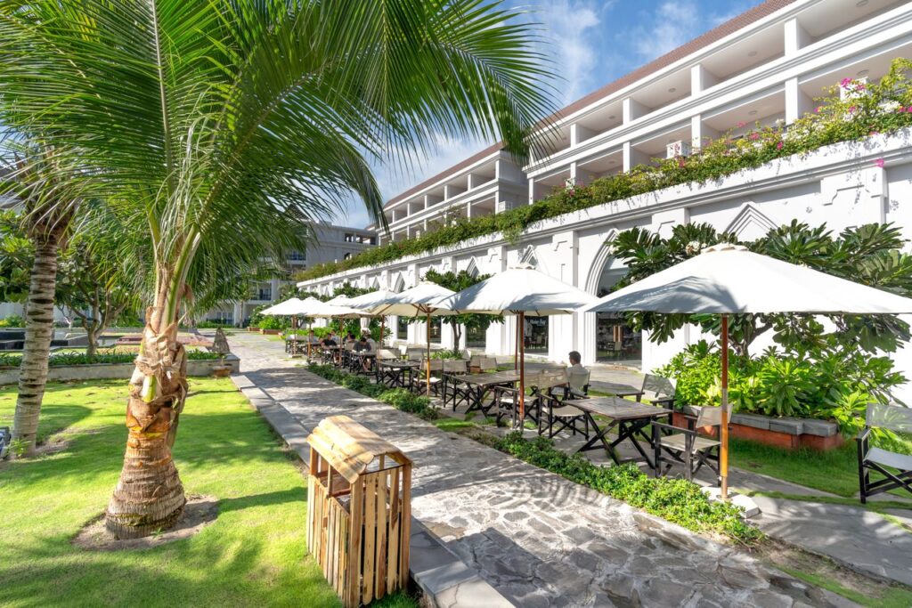 Elegant resort with palm trees, footpath, and seating under umbrellas for a relaxing vacation.