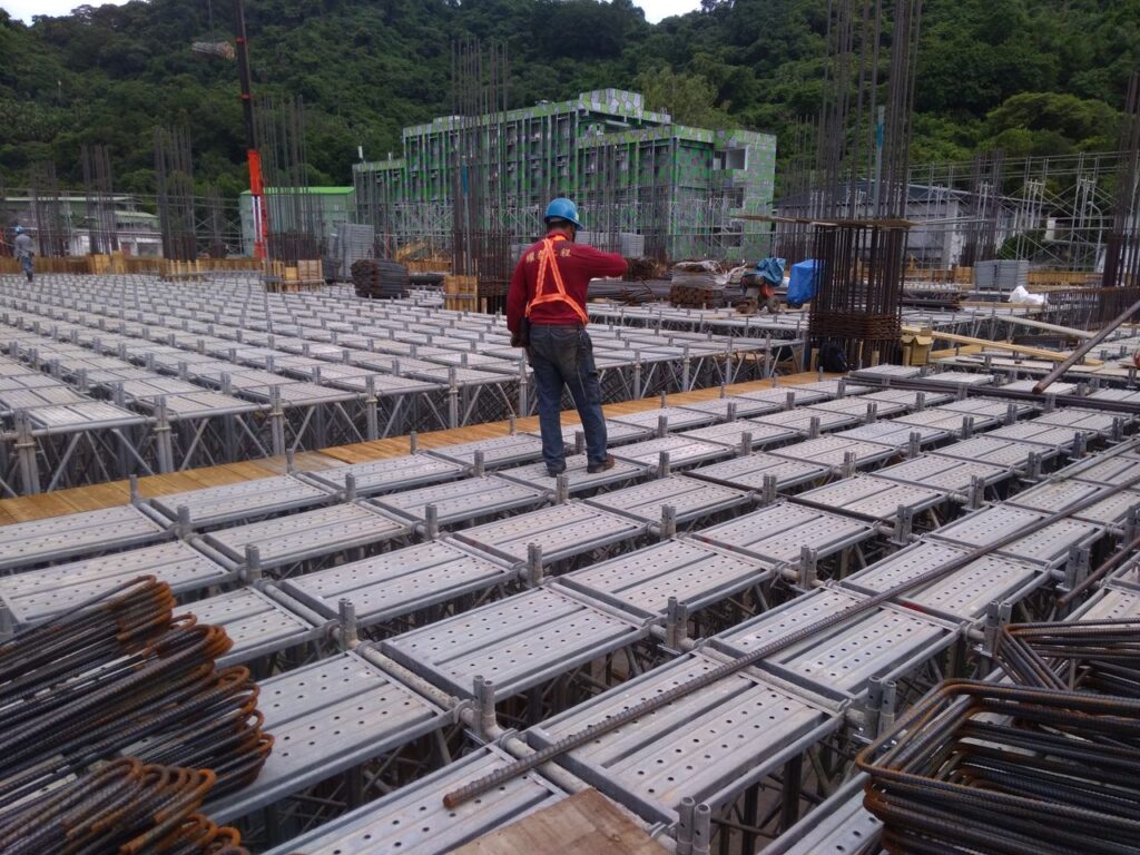 A construction worker inspects scaffolding at a building site in Taiwan, ensuring safety and progress.