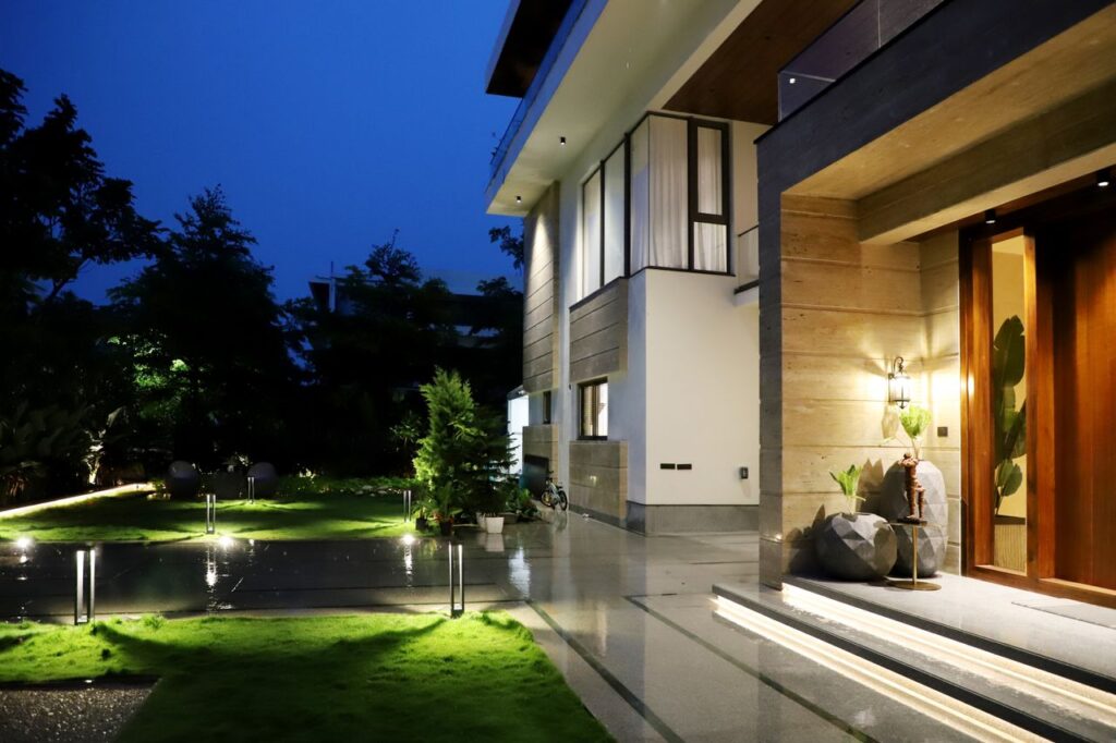 Elegant residential architecture illuminated at night, showcasing modern design and lush garden.
