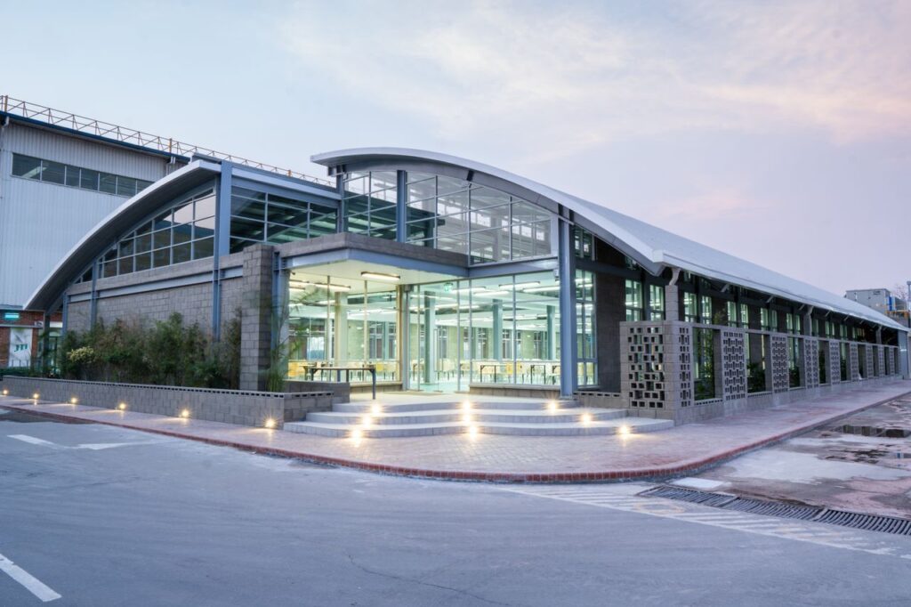 Sleek modern building with illuminated glass entrance and curved roof, showcasing urban architectural design.