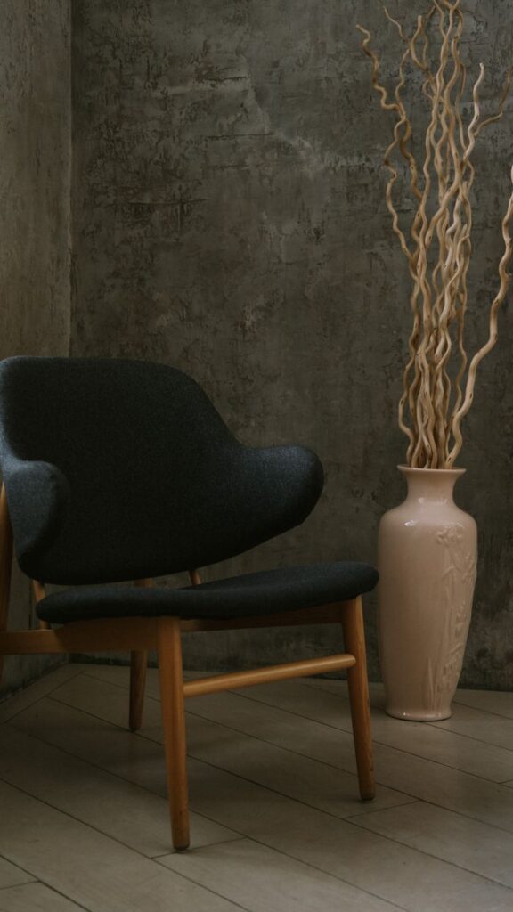 A mid-century modern chair beside a decorative vase in a minimalistic indoor setting.